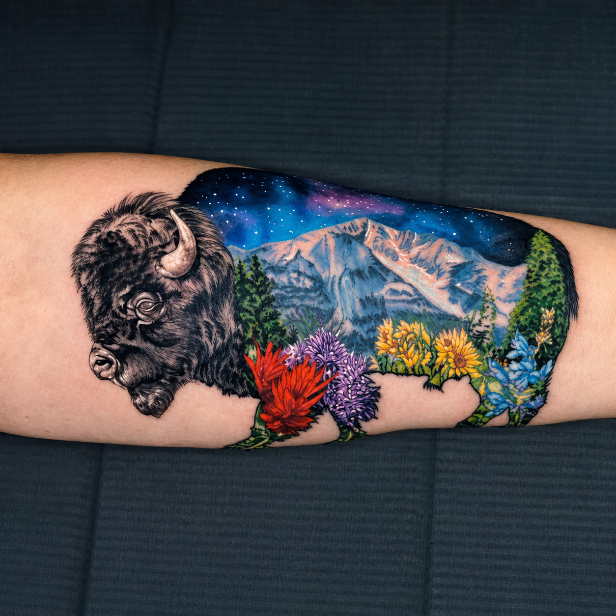 Jami's forearm tattoo of a bison filled with a mountain landscape and wildflowers