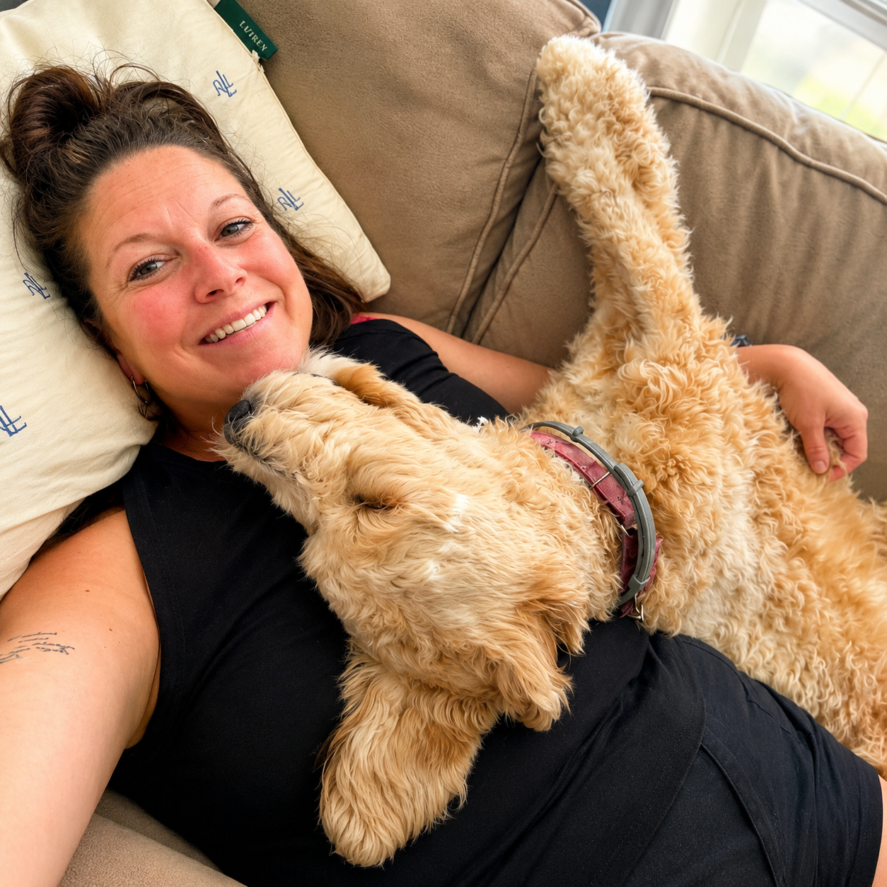 Jami relaxing on the couch cuddling her cream doodle