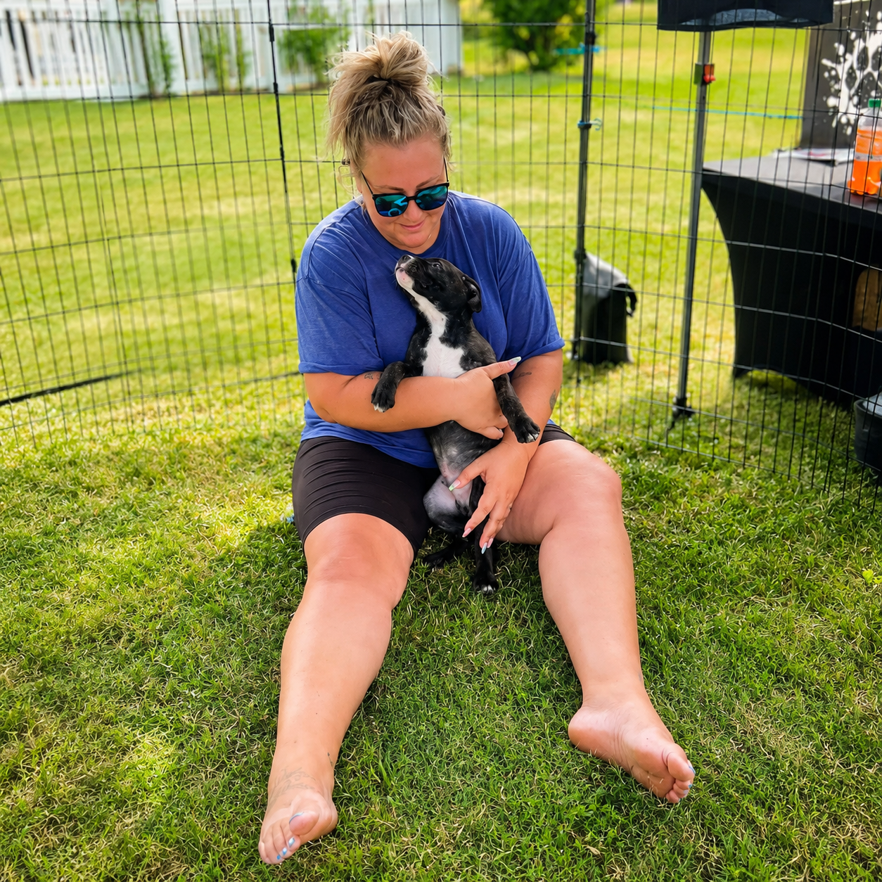 Cristie holding a puppy inside a play pen at an adoption event