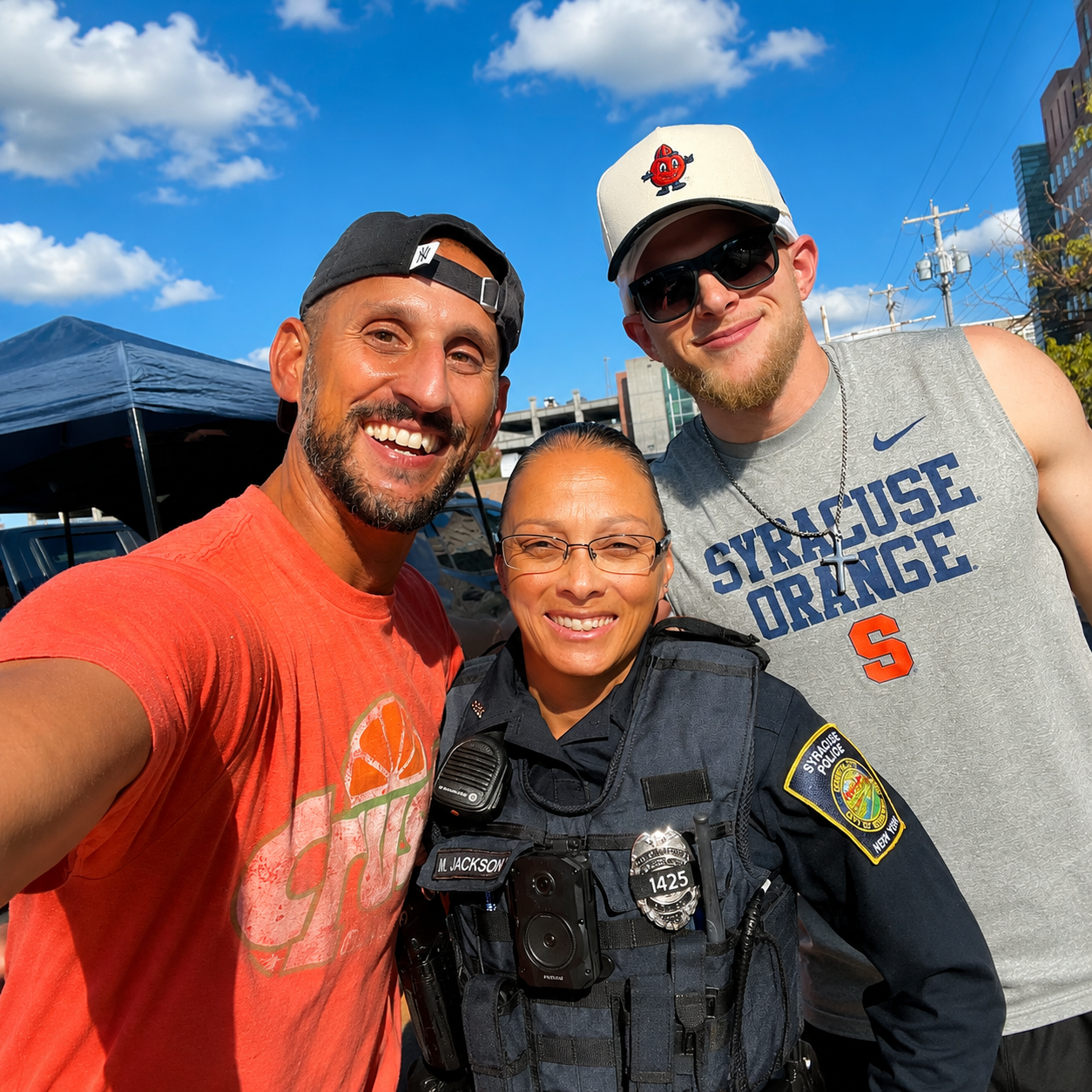 Officer Jackson with two community members at a Syracuse tailgate