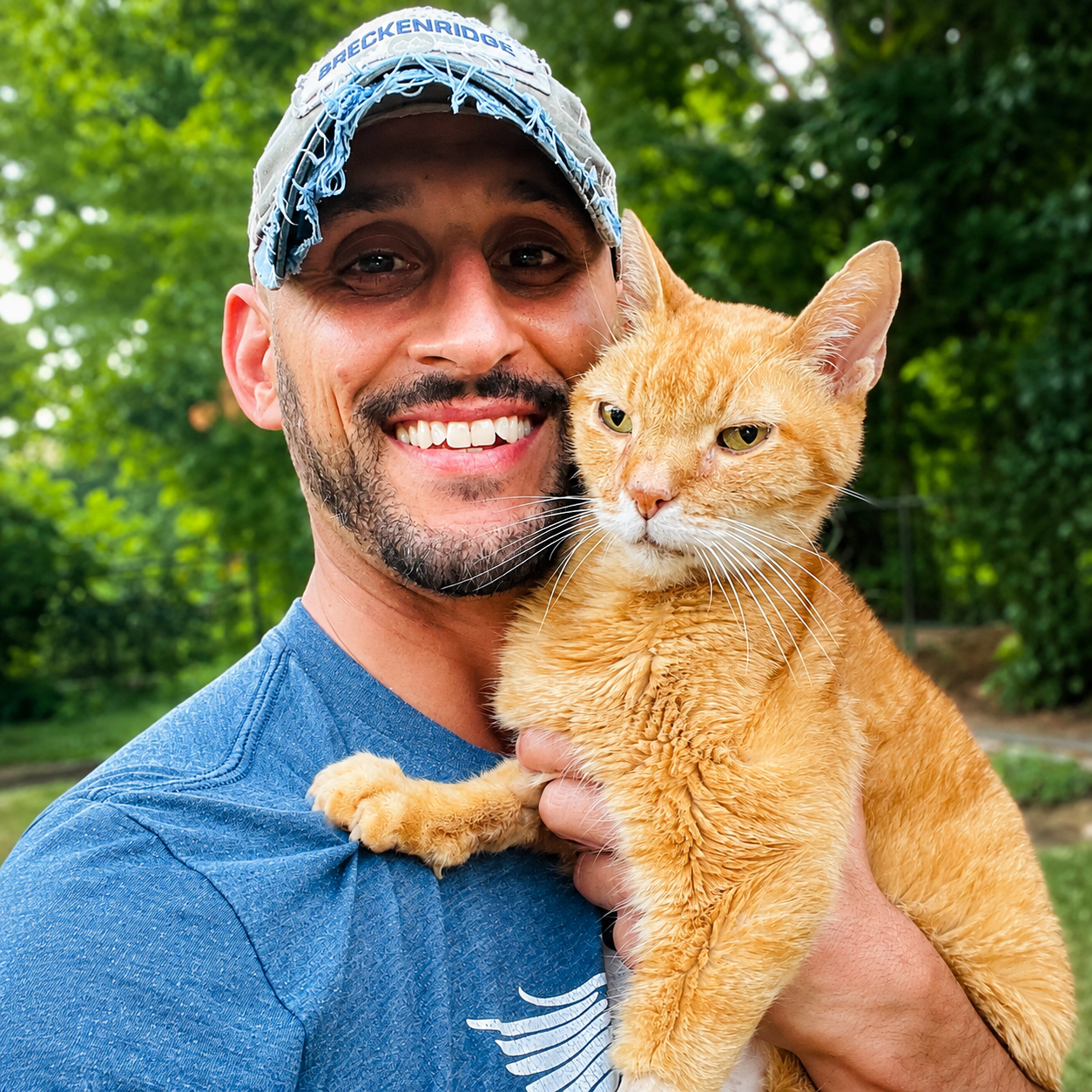 Joseph holding his orange rescue cat cheek to cheek outdoors