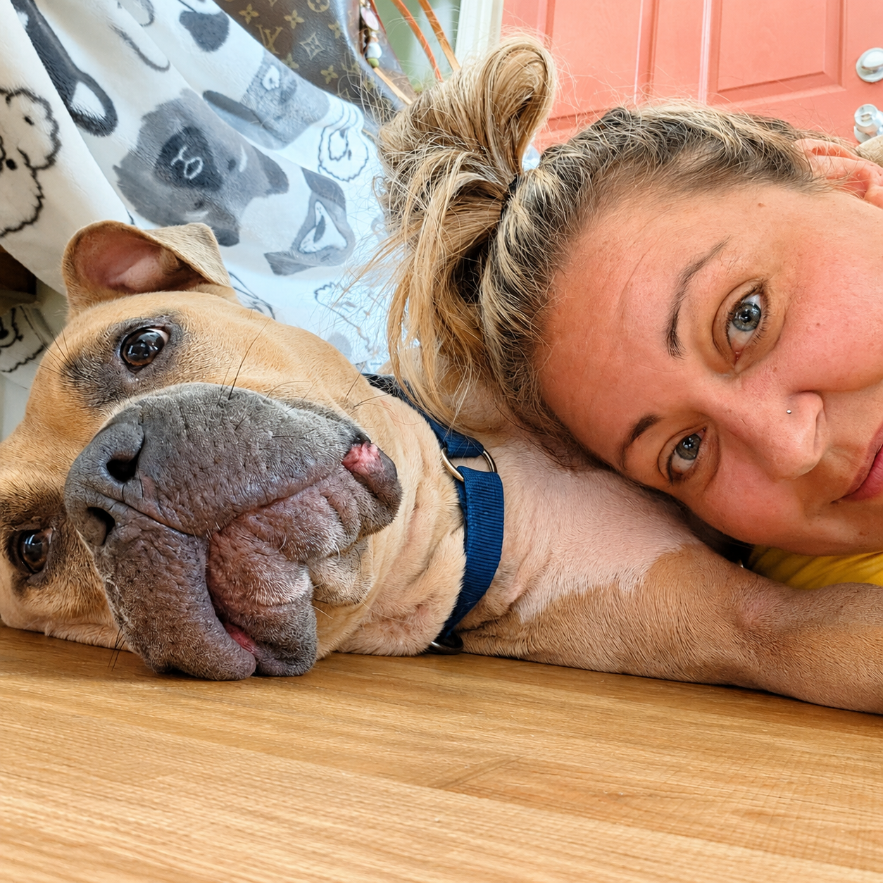 Cristie lying on the floor cheek to cheek with a tan pit bull mix